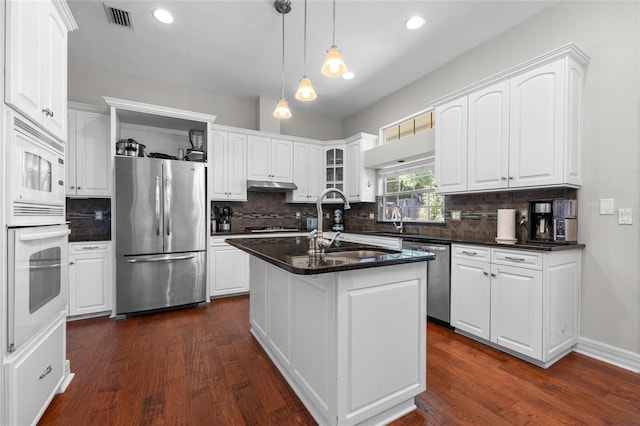 kitchen with stainless steel appliances, under cabinet range hood, white cabinetry, and recessed lighting