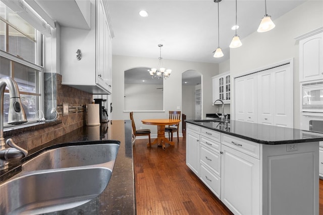 kitchen featuring a sink, white appliances, arched walkways, a chandelier, and recessed lighting