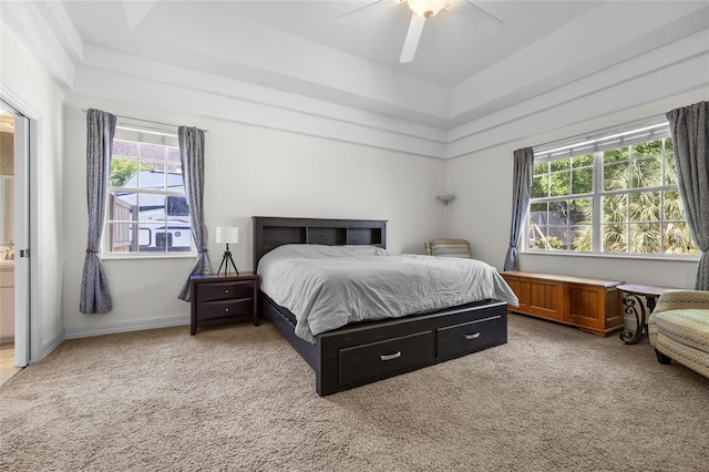 carpeted bedroom with a ceiling fan and a tray ceiling