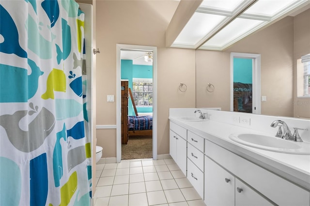 ensuite bathroom with double vanity, tile patterned floors, curtained shower, ceiling fan, and toilet