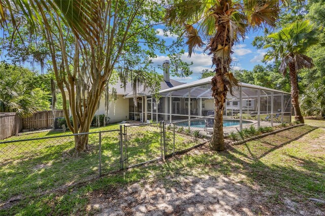 rear view of property featuring a gate, a lanai, and stucco siding