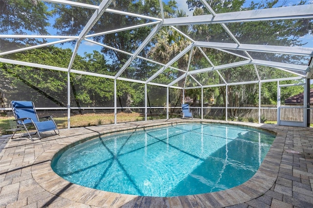 outdoor pool featuring a patio, glass enclosure, and a fenced backyard