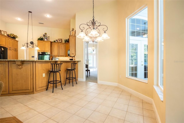 10312 SW 23rd Ave, Gainesville, FL 32607 - kitchen featuring a chandelier, fridge, a kitchen bar, decorative light fixtures, and healthy amount of natural light