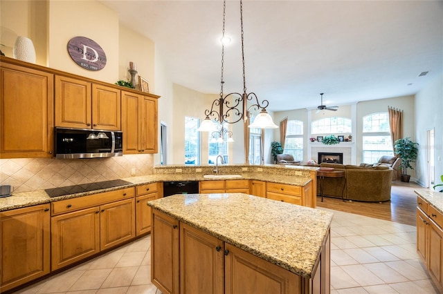 10312 SW 23rd Ave, Gainesville, FL 32607 - kitchen with black appliances, a sink, a fireplace, decorative backsplash, and brown cabinetry