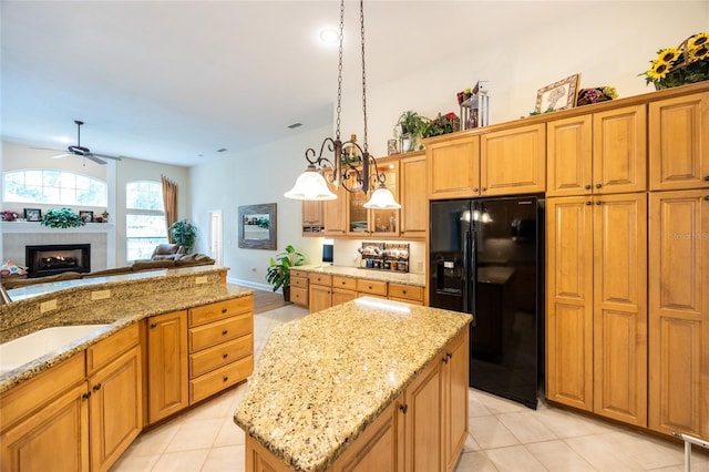 10312 SW 23rd Ave, Gainesville, FL 32607 - kitchen featuring black refrigerator with ice dispenser, light tile patterned flooring, ceiling fan, and light stone countertops