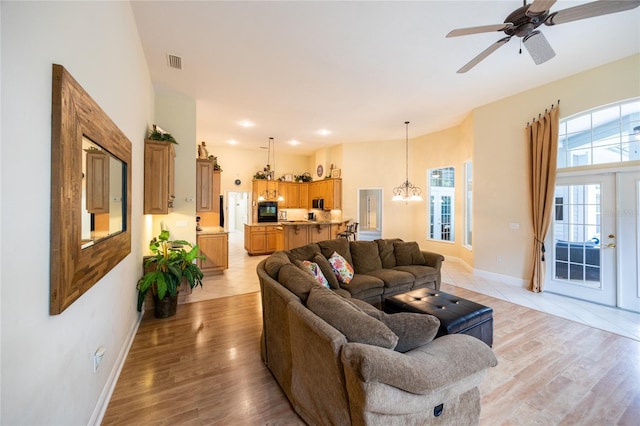 10312 SW 23rd Ave, Gainesville, FL 32607 - living room featuring a chandelier, baseboards, light wood finished floors, and ceiling fan