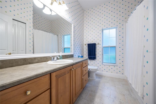 10312 SW 23rd Ave, Gainesville, FL 32607 - bathroom with wallpapered walls, baseboards, vanity, toilet, and stone finish flooring