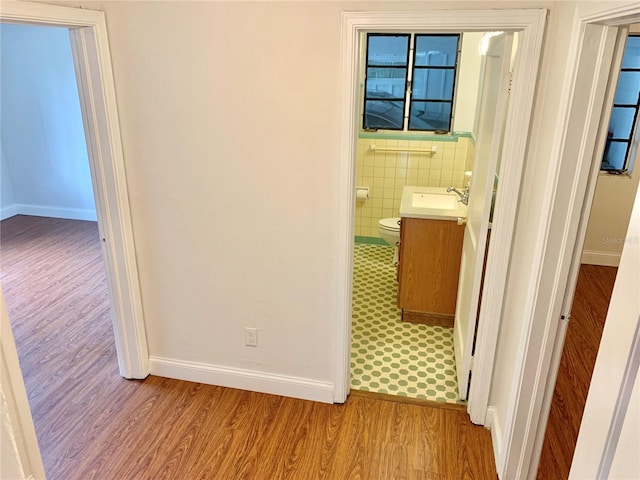 1041 NE 10th Ave, Gainesville, FL 32601 - hall featuring light wood-type flooring, baseboards, tile walls, and a sink