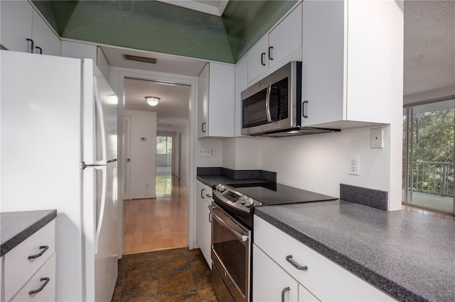 kitchen featuring dark countertops, stainless steel appliances, visible vents, and white cabinets