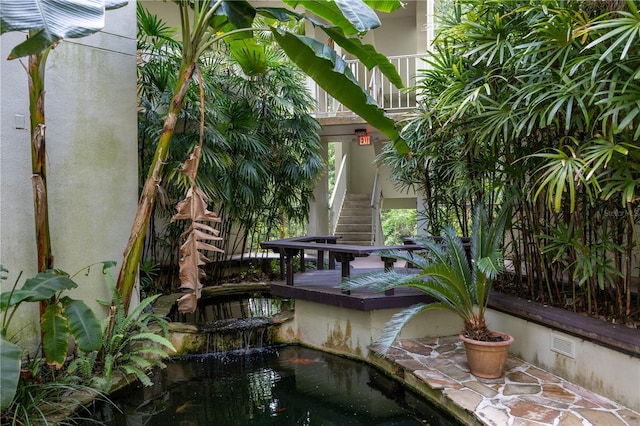 exterior space with a small pond, visible vents, and stairs