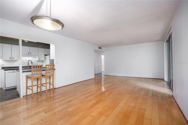living room featuring visible vents, light wood-style floors, and a textured ceiling