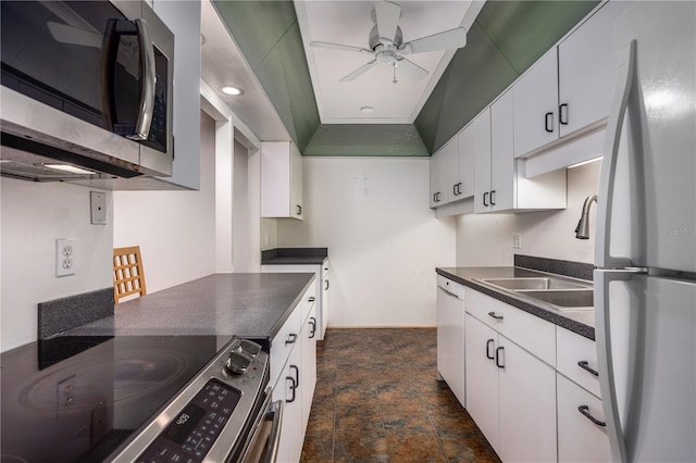 kitchen with a sink, a ceiling fan, dark countertops, white cabinets, and appliances with stainless steel finishes
