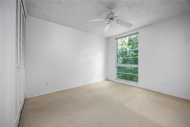 empty room with a textured ceiling, ceiling fan, and carpet floors
