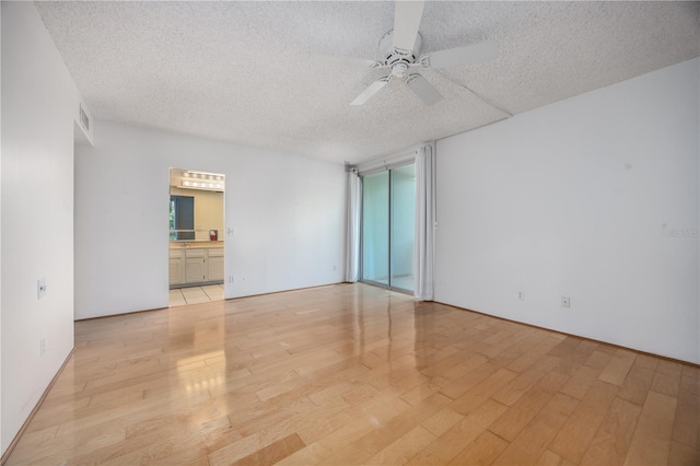 empty room with visible vents, a ceiling fan, a textured ceiling, and light wood finished floors