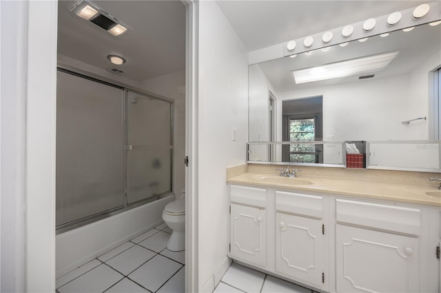full bath with tile patterned floors, combined bath / shower with glass door, double vanity, toilet, and a sink