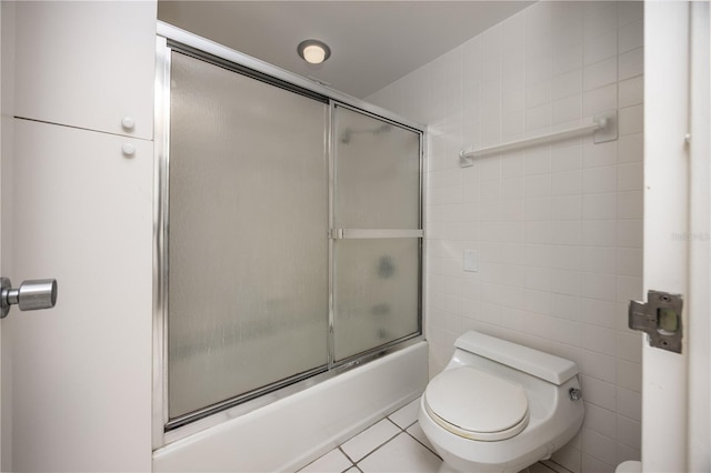 bathroom with combined bath / shower with glass door, tile walls, toilet, and tile patterned flooring
