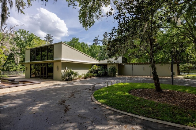 mid-century inspired home featuring curved driveway and stucco siding