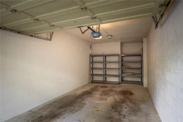 garage with a garage door opener and concrete block wall