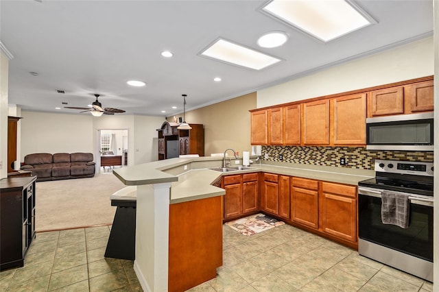 kitchen with a sink, open floor plan, a peninsula, backsplash, and stainless steel appliances