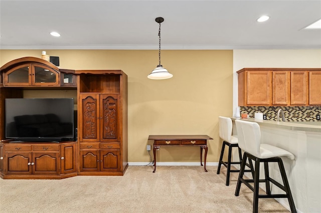 kitchen with light colored carpet, crown molding, decorative backsplash, a kitchen bar, and hanging light fixtures