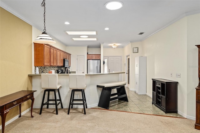 kitchen featuring a breakfast bar, crown molding, a peninsula, and appliances with stainless steel finishes