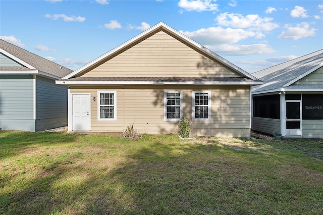 rear view of property with a lawn and a sunroom