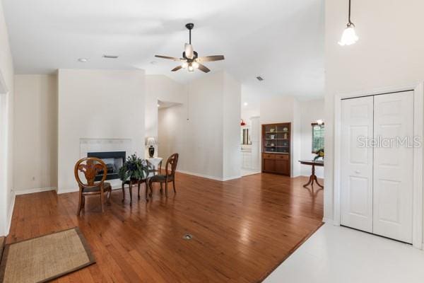23225 NW County Rd 236, High Springs, FL 32643 - interior space with high vaulted ceiling, a glass covered fireplace, ceiling fan, and wood finished floors