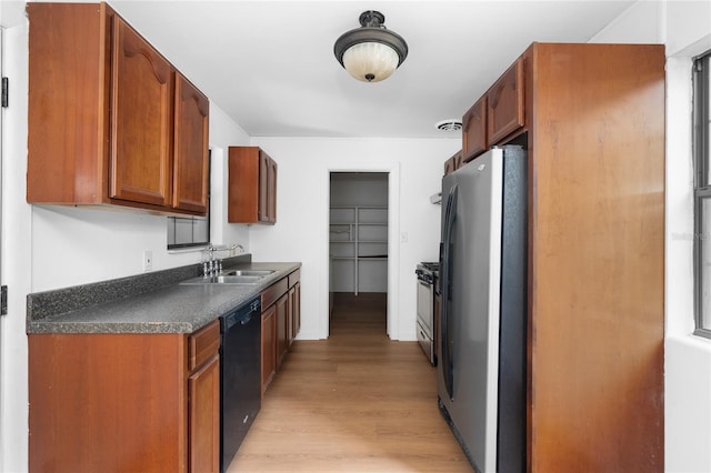 529 NE 12th Ct, Gainesville, FL 32601 - kitchen with appliances with stainless steel finishes, a sink, light wood-style flooring, dark countertops, and brown cabinetry