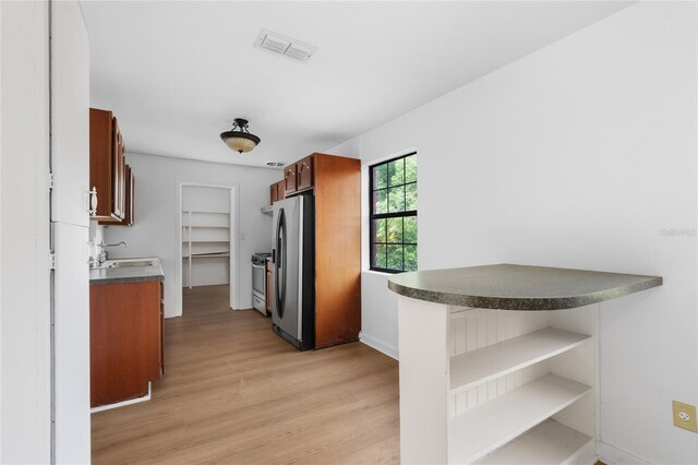 529 NE 12th Ct, Gainesville, FL 32601 - kitchen featuring freestanding refrigerator, dark countertops, light wood-style flooring, a sink, and open shelves