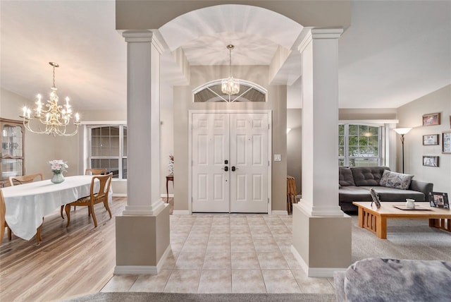 foyer featuring ornate columns, baseboards, and an inviting chandelier