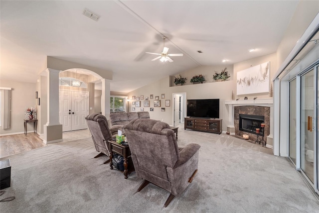 living area with a ceiling fan, decorative columns, light colored carpet, visible vents, and lofted ceiling
