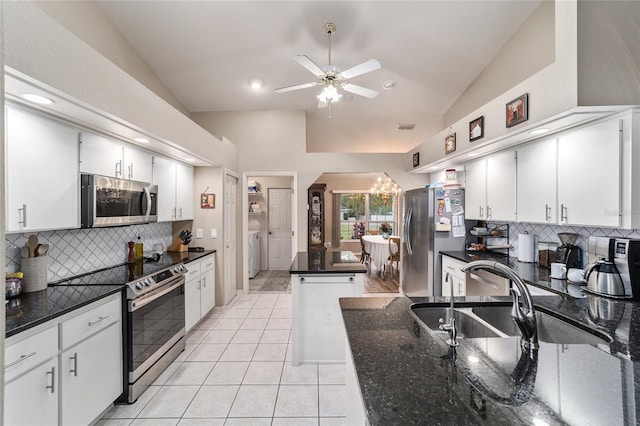 kitchen featuring washer and clothes dryer, a sink, ceiling fan with notable chandelier, vaulted ceiling, and stainless steel appliances