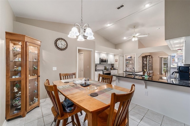 dining space with light tile patterned floors, visible vents, ceiling fan with notable chandelier, and lofted ceiling