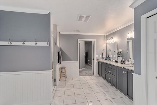 full bath featuring crown molding, a wainscoted wall, double vanity, and visible vents