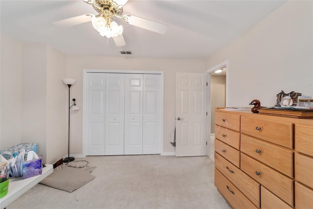 bedroom with a ceiling fan, light colored carpet, visible vents, baseboards, and a closet