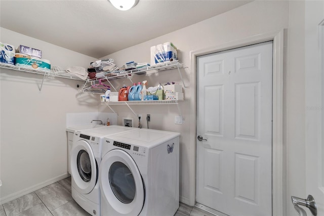 washroom featuring washing machine and clothes dryer, laundry area, and baseboards