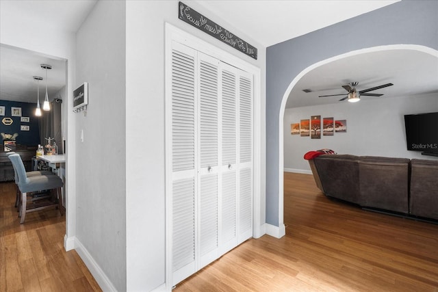 hallway featuring arched walkways, baseboards, and wood finished floors