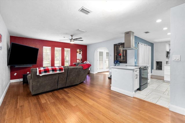 living room with arched walkways, baseboards, light wood-type flooring, and visible vents