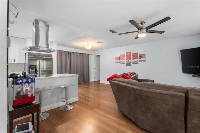living room with a ceiling fan, baseboards, visible vents, and wood finished floors