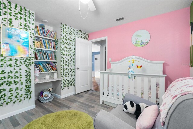 bedroom with a ceiling fan, baseboards, visible vents, and wood finished floors