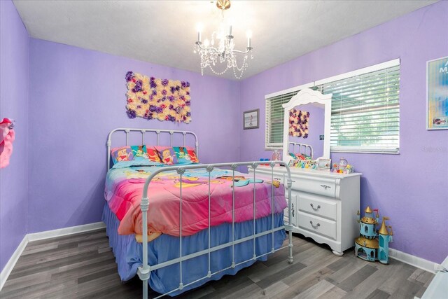 bedroom with baseboards, a notable chandelier, and wood finished floors