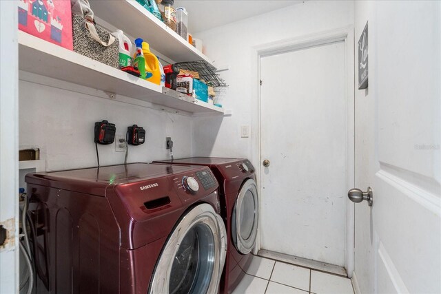 clothes washing area with washing machine and clothes dryer, laundry area, and light tile patterned floors