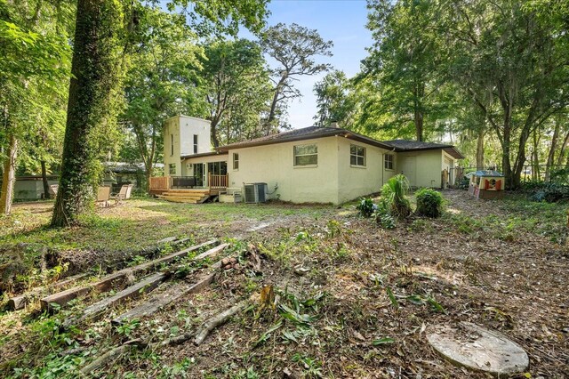 back of property featuring a garden, a wooden deck, central air condition unit, fence, and stucco siding