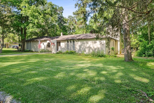 ranch-style house with a chimney and a front yard
