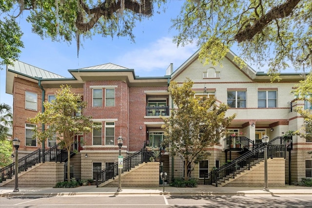 339 NE 2nd Ave, Gainesville, FL 32601 - view of front facade featuring stairway, brick siding, a standing seam roof, and metal roof