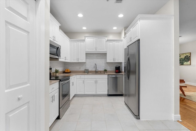 339 NE 2nd Ave, Gainesville, FL 32601 - kitchen with white cabinets, stainless steel appliances, a sink, and tasteful backsplash