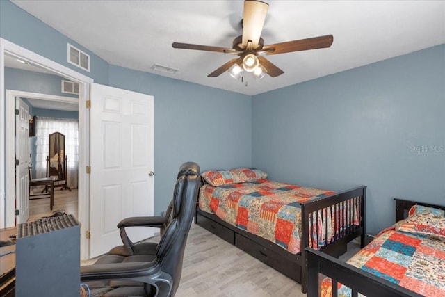 bedroom featuring wood finished floors, visible vents, and a ceiling fan