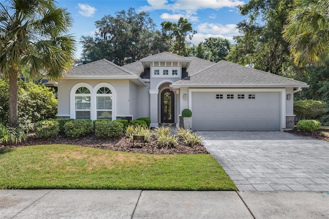 555 NW 134th Way, Newberry, FL 32669 - mediterranean / spanish home with a front yard, a garage, decorative driveway, a shingled roof, and stucco siding