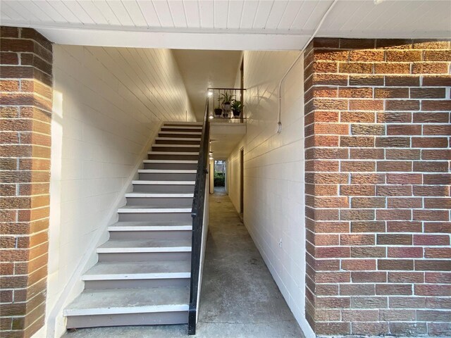staircase with brick wall and concrete floors