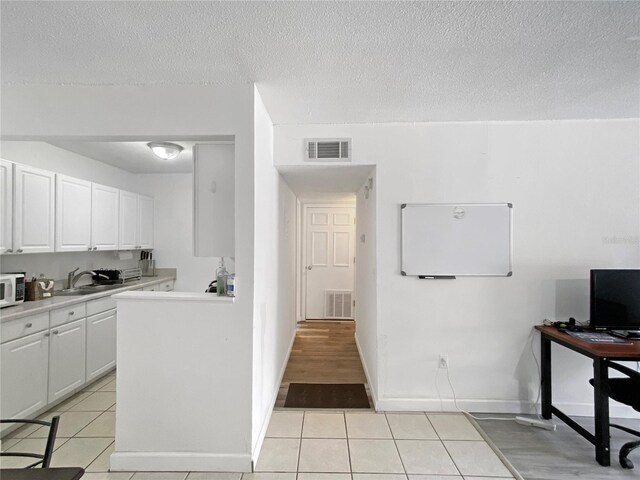 kitchen with a sink, light tile patterned floors, white microwave, and visible vents